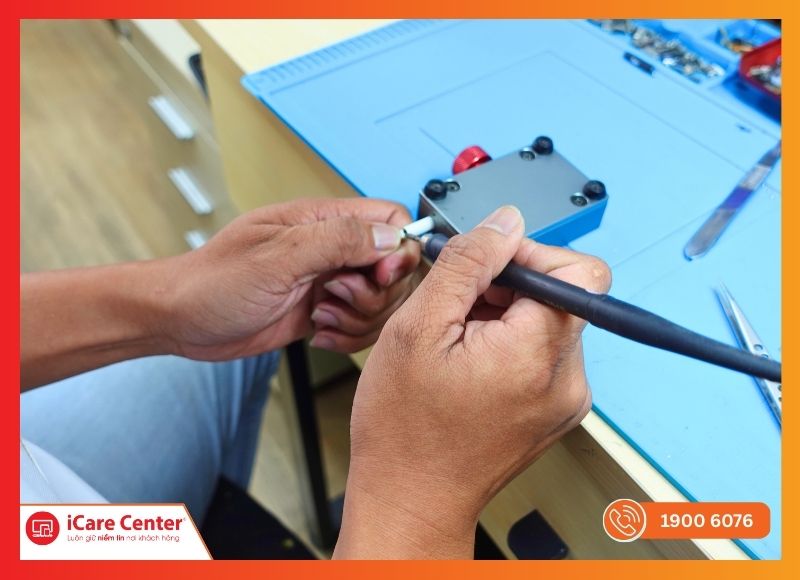 Kỹ thuật viên iCare Center sử dụng thiết bị chuyên dụng để tách vỏ AirPods 2